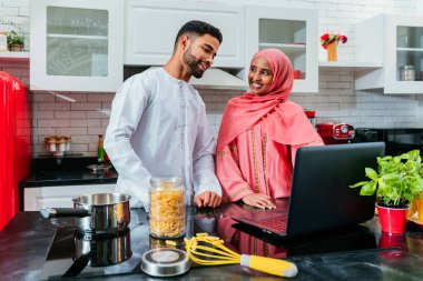 Geleneksel Arap kıyafetleri içinde mutlu bir orta doğu çifti - evli Arap karı-koca evde birbirine bağlanıyor, ilişki kavramları, ev hayatı ve emirati yaşam tarzı