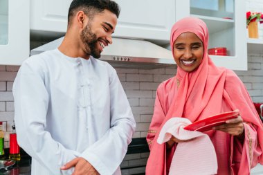 Geleneksel Arap kıyafetleri içinde mutlu bir orta doğu çifti - evli Arap karı-koca evde birbirine bağlanıyor, ilişki kavramları, ev hayatı ve emirati yaşam tarzı