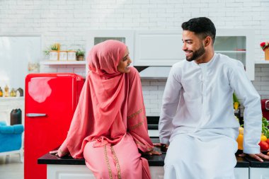 Geleneksel Arap kıyafetleri içinde mutlu bir orta doğu çifti - evli Arap karı-koca evde birbirine bağlanıyor, ilişki kavramları, ev hayatı ve emirati yaşam tarzı
