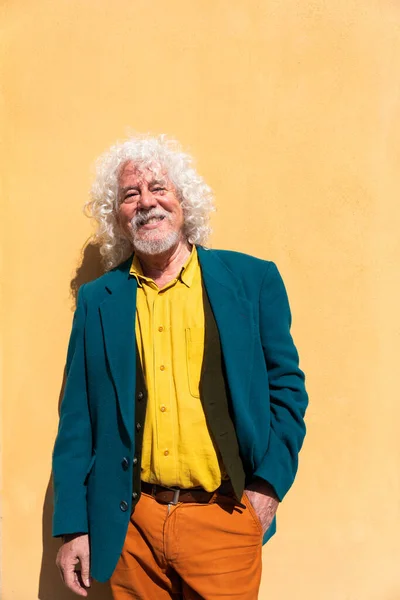 一位英俊的老年男子穿着五颜六色的黄墙背景服装的画像 — 图库照片