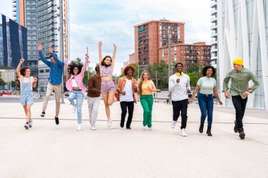 Açık havada kaynaşan neşeli çoklu etnik kökenli genç arkadaş grubu - çok ırklı öğrenciler şehirde buluşuyor, gençlik kavramları, insan yaşam tarzı, çeşitlilik, gençlik ve şehir hayatı