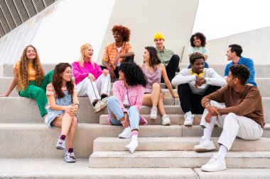 Açık havada kaynaşan neşeli çoklu etnik kökenli genç arkadaş grubu - çok ırklı öğrenciler şehirde buluşuyor, gençlik kavramları, insan yaşam tarzı, çeşitlilik, gençlik ve şehir hayatı