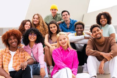 Açık havada kaynaşan neşeli çoklu etnik kökenli genç arkadaş grubu - çok ırklı öğrenciler şehirde buluşuyor, gençlik kavramları, insan yaşam tarzı, çeşitlilik, gençlik ve şehir hayatı