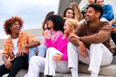 Açık havada kaynaşan neşeli çoklu etnik kökenli genç arkadaş grubu - çok ırklı öğrenciler şehirde buluşuyor, gençlik kavramları, insan yaşam tarzı, çeşitlilik, gençlik ve şehir hayatı