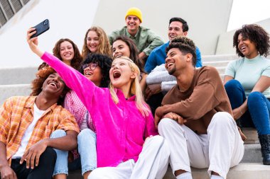 Açık havada kaynaşan neşeli çoklu etnik kökenli genç arkadaş grubu - çok ırklı öğrenciler şehirde buluşuyor, gençlik kavramları, insan yaşam tarzı, çeşitlilik, gençlik ve şehir hayatı