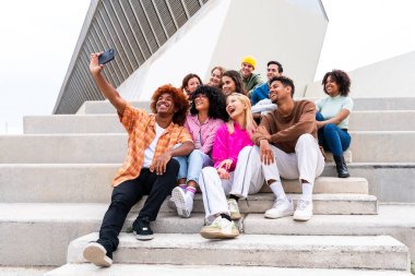 Açık havada kaynaşan neşeli çoklu etnik kökenli genç arkadaş grubu - çok ırklı öğrenciler şehirde buluşuyor, gençlik kavramları, insan yaşam tarzı, çeşitlilik, gençlik ve şehir hayatı