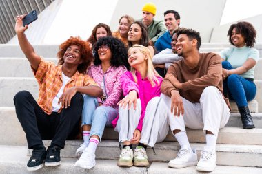 Açık havada kaynaşan neşeli çoklu etnik kökenli genç arkadaş grubu - çok ırklı öğrenciler şehirde buluşuyor, gençlik kavramları, insan yaşam tarzı, çeşitlilik, gençlik ve şehir hayatı