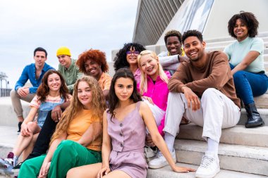 Açık havada kaynaşan neşeli çoklu etnik kökenli genç arkadaş grubu - çok ırklı öğrenciler şehirde buluşuyor, gençlik kavramları, insan yaşam tarzı, çeşitlilik, gençlik ve şehir hayatı