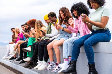 Açık havada kaynaşan neşeli çoklu etnik kökenli genç arkadaş grubu - çok ırklı öğrenciler şehirde buluşuyor, gençlik kavramları, insan yaşam tarzı, çeşitlilik, gençlik ve şehir hayatı