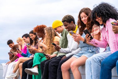 Açık havada kaynaşan neşeli çoklu etnik kökenli genç arkadaş grubu - çok ırklı öğrenciler şehirde buluşuyor, gençlik kavramları, insan yaşam tarzı, çeşitlilik, gençlik ve şehir hayatı