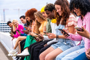 Açık havada kaynaşan neşeli çoklu etnik kökenli genç arkadaş grubu - çok ırklı öğrenciler şehirde buluşuyor, gençlik kavramları, insan yaşam tarzı, çeşitlilik, gençlik ve şehir hayatı