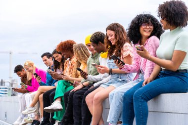 Açık havada kaynaşan neşeli çoklu etnik kökenli genç arkadaş grubu - çok ırklı öğrenciler şehirde buluşuyor, gençlik kavramları, insan yaşam tarzı, çeşitlilik, gençlik ve şehir hayatı