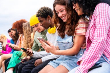 Açık havada kaynaşan neşeli çoklu etnik kökenli genç arkadaş grubu - çok ırklı öğrenciler şehirde buluşuyor, gençlik kavramları, insan yaşam tarzı, çeşitlilik, gençlik ve şehir hayatı