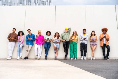 Açık havada kaynaşan neşeli çoklu etnik kökenli genç arkadaş grubu - çok ırklı öğrenciler şehirde buluşuyor, gençlik kavramları, insan yaşam tarzı, çeşitlilik, gençlik ve şehir hayatı