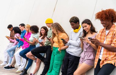 Açık havada kaynaşan neşeli çoklu etnik kökenli genç arkadaş grubu - çok ırklı öğrenciler şehirde buluşuyor, gençlik kavramları, insan yaşam tarzı, çeşitlilik, gençlik ve şehir hayatı