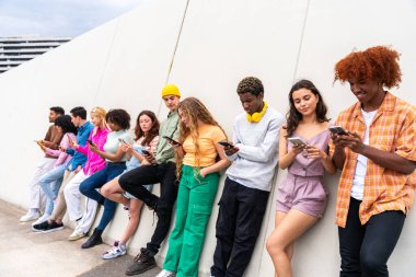 Açık havada kaynaşan neşeli çoklu etnik kökenli genç arkadaş grubu - çok ırklı öğrenciler şehirde buluşuyor, gençlik kavramları, insan yaşam tarzı, çeşitlilik, gençlik ve şehir hayatı