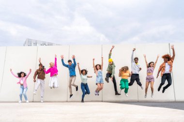 Açık havada kaynaşan neşeli çoklu etnik kökenli genç arkadaş grubu - çok ırklı öğrenciler şehirde buluşuyor, gençlik kavramları, insan yaşam tarzı, çeşitlilik, gençlik ve şehir hayatı