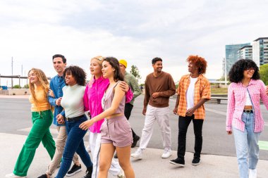 Açık havada kaynaşan neşeli çoklu etnik kökenli genç arkadaş grubu - çok ırklı öğrenciler şehirde buluşuyor, gençlik kavramları, insan yaşam tarzı, çeşitlilik, gençlik ve şehir hayatı