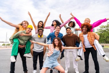 Açık havada kaynaşan neşeli çoklu etnik kökenli genç arkadaş grubu - çok ırklı öğrenciler şehirde buluşuyor, gençlik kavramları, insan yaşam tarzı, çeşitlilik, gençlik ve şehir hayatı