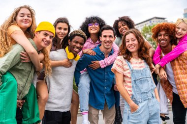 Açık havada kaynaşan neşeli çoklu etnik kökenli genç arkadaş grubu - çok ırklı öğrenciler şehirde buluşuyor, gençlik kavramları, insan yaşam tarzı, çeşitlilik, gençlik ve şehir hayatı