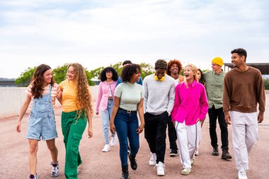 Açık havada kaynaşan neşeli çoklu etnik kökenli genç arkadaş grubu - çok ırklı öğrenciler şehirde buluşuyor, gençlik kavramları, insan yaşam tarzı, çeşitlilik, gençlik ve şehir hayatı