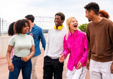 Açık havada kaynaşan neşeli çoklu etnik kökenli genç arkadaş grubu - çok ırklı öğrenciler şehirde buluşuyor, gençlik kavramları, insan yaşam tarzı, çeşitlilik, gençlik ve şehir hayatı