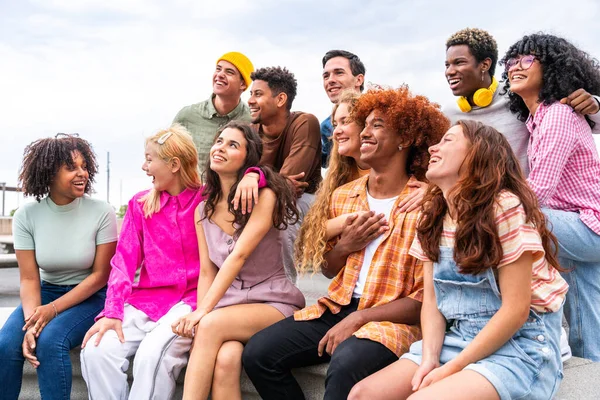 Happy playful multiethnic group of young friends bonding outdoors - Multiracial millennials students meeting in the city, concepts of youth, people lifestyle, diversity, teenage and urban life
