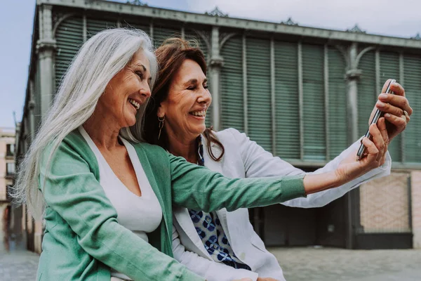Beautiful senior women bonding outdoors in the city - Attractive cheerful mature female friends having fun, shopping and bonding, concepts about elderly lifestyle