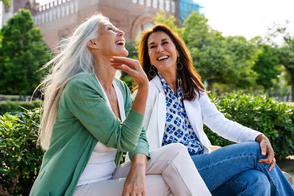 Beautiful senior women bonding outdoors in the city - Attractive cheerful mature female friends having fun, shopping and bonding, concepts about elderly lifestyle