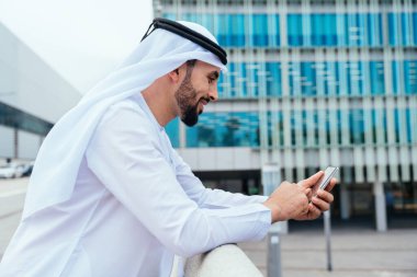 Arap Ortadoğu 'lu, Emirati Kandora giysili, şehirde geleneksel giysiler giyen Arap Müslüman iş adamı, şehir iş merkezinde geziniyor..