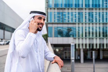 Arap Ortadoğu 'lu, Emirati Kandora giysili, şehirde geleneksel giysiler giyen Arap Müslüman iş adamı, şehir iş merkezinde geziniyor..