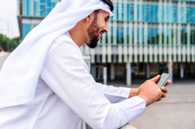 Arap Ortadoğu 'lu, Emirati Kandora giysili, şehirde geleneksel giysiler giyen Arap Müslüman iş adamı, şehir iş merkezinde geziniyor..