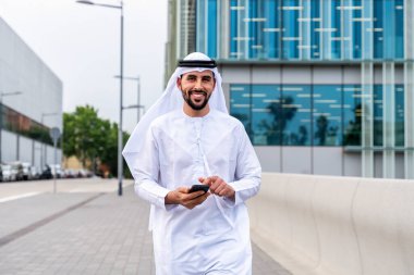 Arap Ortadoğu 'lu, Emirati Kandora giysili, şehirde geleneksel giysiler giyen Arap Müslüman iş adamı, şehir iş merkezinde geziniyor..