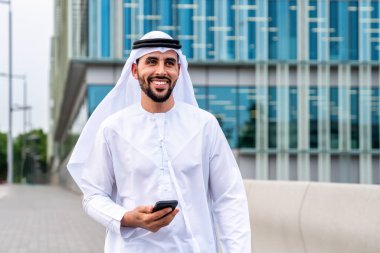 Arap Ortadoğu 'lu, Emirati Kandora giysili, şehirde geleneksel giysiler giyen Arap Müslüman iş adamı, şehir iş merkezinde geziniyor..