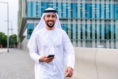 Arap Ortadoğu 'lu, Emirati Kandora giysili, şehirde geleneksel giysiler giyen Arap Müslüman iş adamı, şehir iş merkezinde geziniyor..