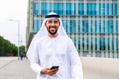 Arap Ortadoğu 'lu, Emirati Kandora giysili, şehirde geleneksel giysiler giyen Arap Müslüman iş adamı, şehir iş merkezinde geziniyor..