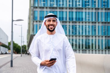 Arap Ortadoğu 'lu, Emirati Kandora giysili, şehirde geleneksel giysiler giyen Arap Müslüman iş adamı, şehir iş merkezinde geziniyor..