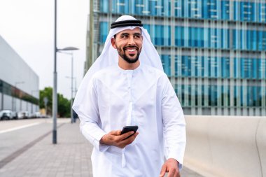 Arap Ortadoğu 'lu, Emirati Kandora giysili, şehirde geleneksel giysiler giyen Arap Müslüman iş adamı, şehir iş merkezinde geziniyor..