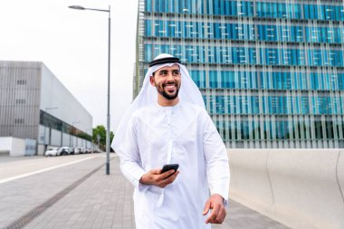 Arap Ortadoğu 'lu, Emirati Kandora giysili, şehirde geleneksel giysiler giyen Arap Müslüman iş adamı, şehir iş merkezinde geziniyor..