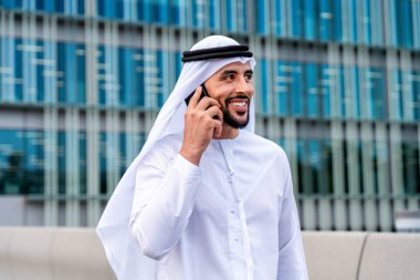 Arap Ortadoğu 'lu, Emirati Kandora giysili, şehirde geleneksel giysiler giyen Arap Müslüman iş adamı, şehir iş merkezinde geziniyor..