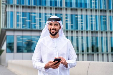Arap Ortadoğu 'lu, Emirati Kandora giysili, şehirde geleneksel giysiler giyen Arap Müslüman iş adamı, şehir iş merkezinde geziniyor..