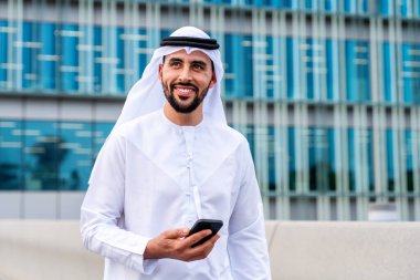 Arap Ortadoğu 'lu, Emirati Kandora giysili, şehirde geleneksel giysiler giyen Arap Müslüman iş adamı, şehir iş merkezinde geziniyor..