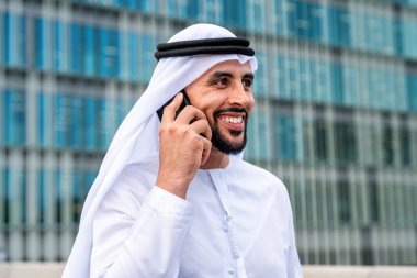 Arap Ortadoğu 'lu, Emirati Kandora giysili, şehirde geleneksel giysiler giyen Arap Müslüman iş adamı, şehir iş merkezinde geziniyor..