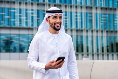 Arap Ortadoğu 'lu, Emirati Kandora giysili, şehirde geleneksel giysiler giyen Arap Müslüman iş adamı, şehir iş merkezinde geziniyor..