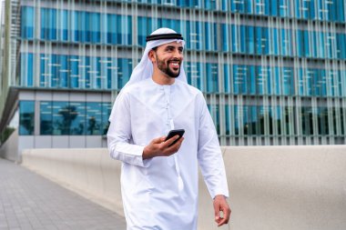 Arap Ortadoğu 'lu, Emirati Kandora giysili, şehirde geleneksel giysiler giyen Arap Müslüman iş adamı, şehir iş merkezinde geziniyor..