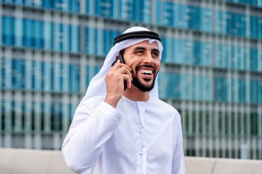 Arap Ortadoğu 'lu, Emirati Kandora giysili, şehirde geleneksel giysiler giyen Arap Müslüman iş adamı, şehir iş merkezinde geziniyor..