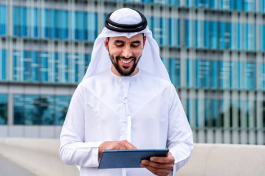 Arap Ortadoğu 'lu, Emirati Kandora giysili, şehirde geleneksel giysiler giyen Arap Müslüman iş adamı, şehir iş merkezinde geziniyor..