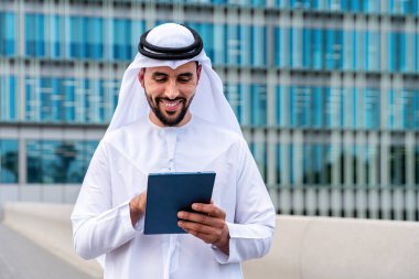 Arap Ortadoğu 'lu, Emirati Kandora giysili, şehirde geleneksel giysiler giyen Arap Müslüman iş adamı, şehir iş merkezinde geziniyor..