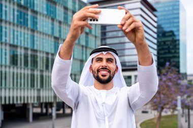 Arap Ortadoğu 'lu, Emirati Kandora giysili, şehirde geleneksel giysiler giyen Arap Müslüman iş adamı, şehir iş merkezinde geziniyor..