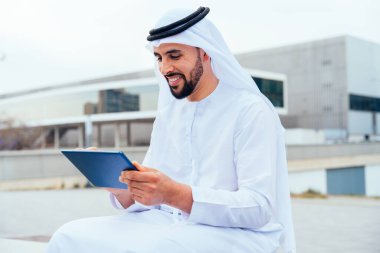 Arap Ortadoğu 'lu, Emirati Kandora giysili, şehirde geleneksel giysiler giyen Arap Müslüman iş adamı, şehir iş merkezinde geziniyor..